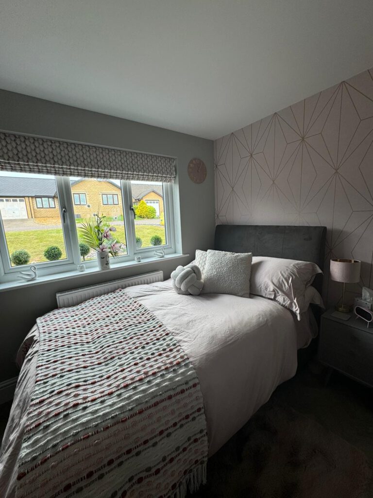 Bedroom with pink geometric feature wallpaper