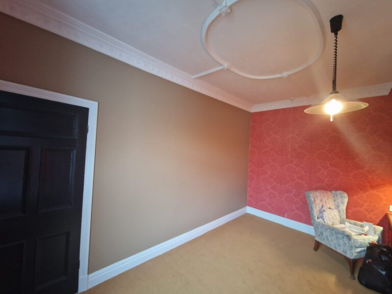 Room with red patterned feature wallpaper and taupe walls
