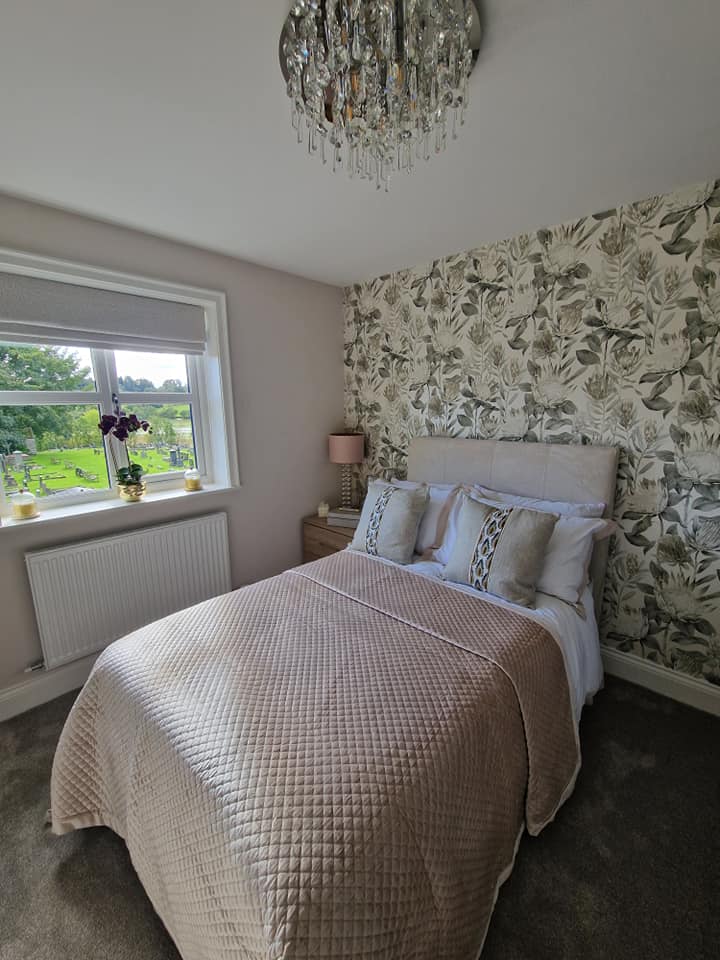 Bedroom with green bird-print feature wallpaper